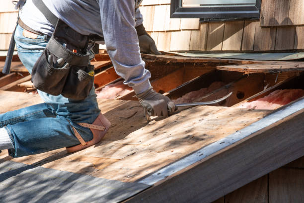 Roofer removing old roof with crowbar